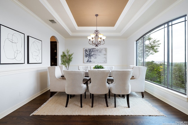 dining room with dark hardwood / wood-style floors, a raised ceiling, crown molding, and a healthy amount of sunlight