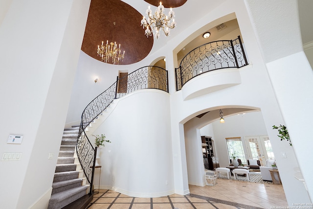 staircase with tile patterned flooring, a chandelier, and a towering ceiling