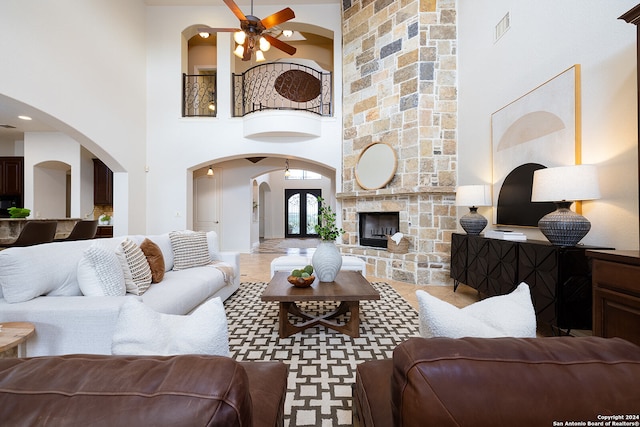 living room featuring ceiling fan, a towering ceiling, and a fireplace