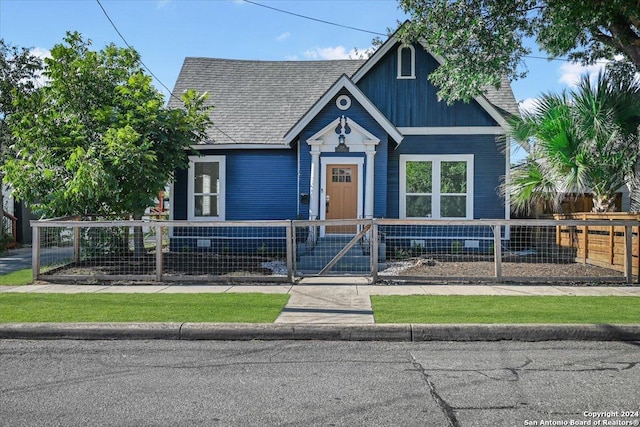 view of front facade with a fenced front yard, a gate, and roof with shingles