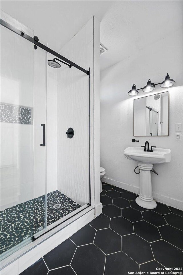 bathroom featuring sink, toilet, an enclosed shower, and tile patterned flooring