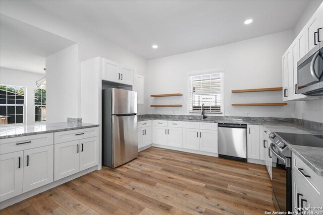 kitchen featuring stainless steel appliances, white cabinets, and light hardwood / wood-style flooring