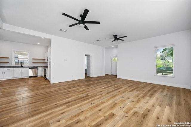 unfurnished living room with ceiling fan, sink, and light wood-type flooring