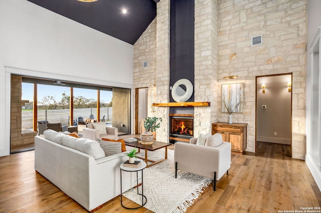 living room with a fireplace, high vaulted ceiling, and hardwood / wood-style flooring