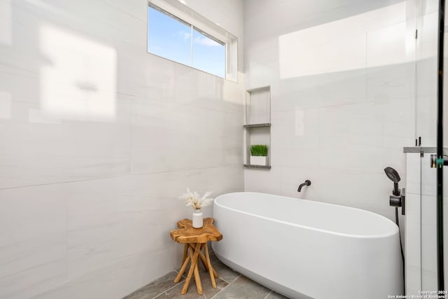 bathroom with tile patterned flooring and a tub to relax in