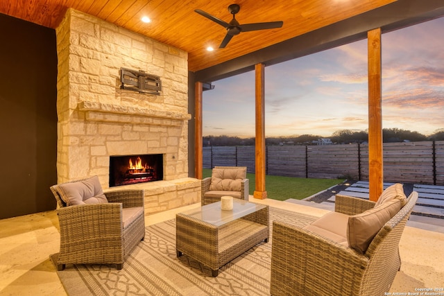 patio terrace at dusk featuring ceiling fan and an outdoor living space with a fireplace