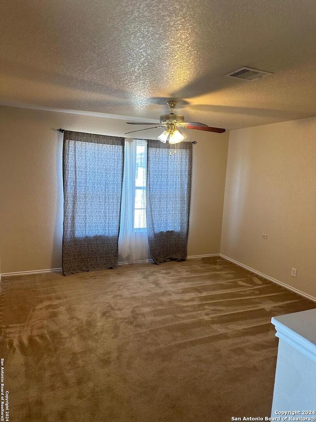 empty room featuring ceiling fan, carpet, and a textured ceiling