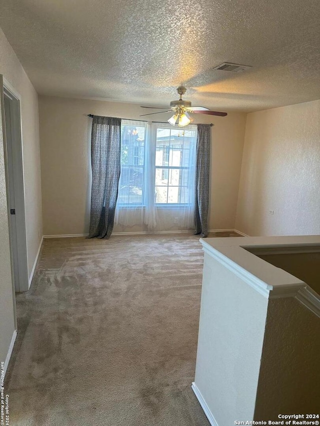 spare room featuring a textured ceiling, carpet flooring, and ceiling fan