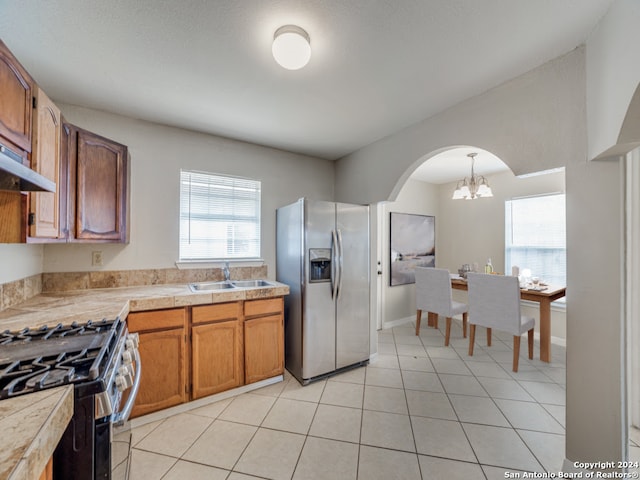 kitchen featuring hanging light fixtures, appliances with stainless steel finishes, light tile patterned floors, sink, and a notable chandelier