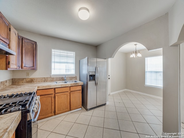 kitchen featuring light tile patterned flooring, stainless steel appliances, a notable chandelier, and a healthy amount of sunlight