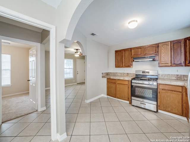 kitchen featuring light tile patterned flooring, gas range, and ceiling fan