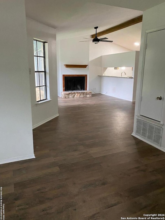 unfurnished living room featuring ceiling fan, lofted ceiling with beams, and dark wood-type flooring