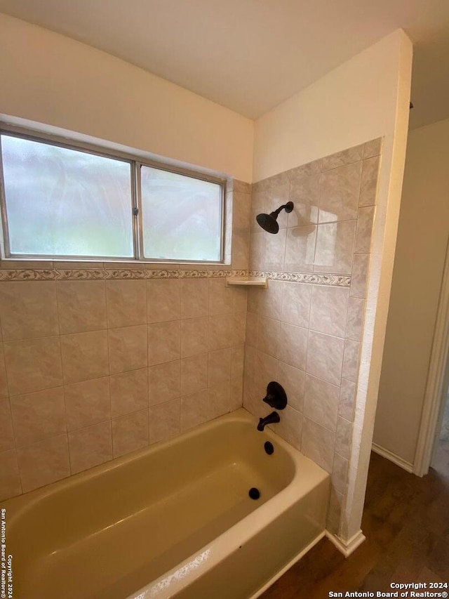 bathroom with hardwood / wood-style floors and tiled shower / bath