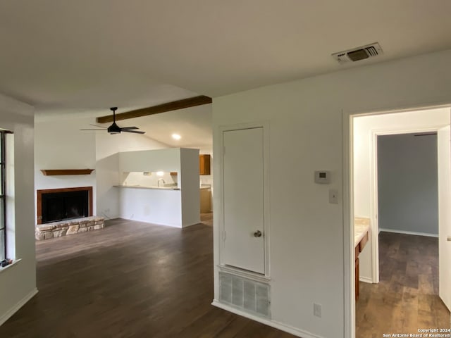 unfurnished living room with a stone fireplace, vaulted ceiling, dark wood-type flooring, and ceiling fan