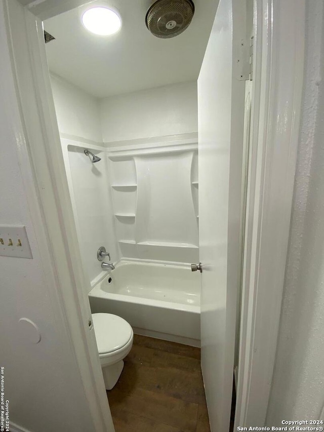 bathroom featuring hardwood / wood-style flooring, shower / bath combination, and toilet