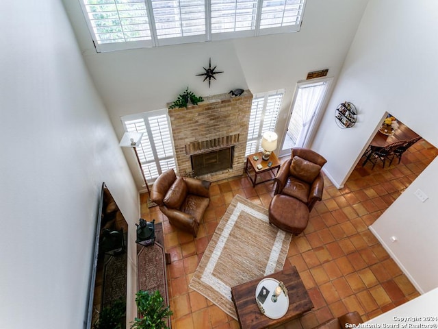 living room with a fireplace, a towering ceiling, baseboards, and tile patterned floors