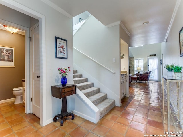 stairway with ornamental molding, baseboards, and tile patterned floors