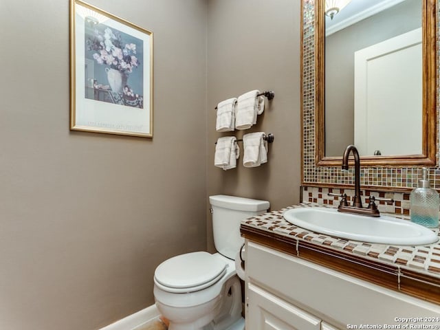 half bath with tasteful backsplash, baseboards, vanity, and toilet