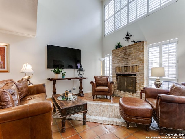 living area with a brick fireplace, a healthy amount of sunlight, crown molding, and light tile patterned floors