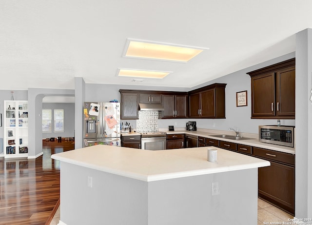 kitchen with light wood-type flooring, a kitchen island, sink, stainless steel appliances, and dark brown cabinets