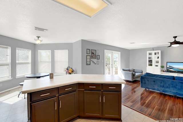 kitchen with ceiling fan, dark brown cabinetry, french doors, light tile patterned floors, and a textured ceiling