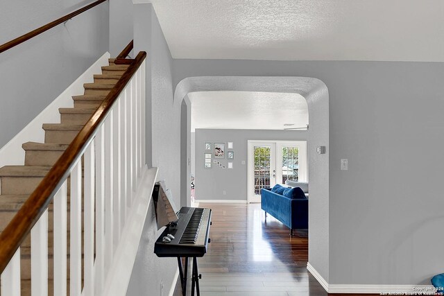 staircase featuring hardwood / wood-style floors, french doors, and a textured ceiling