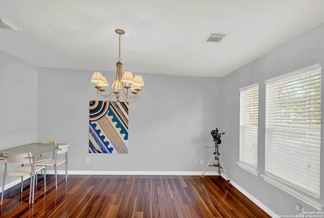 unfurnished dining area featuring a notable chandelier and dark wood-type flooring