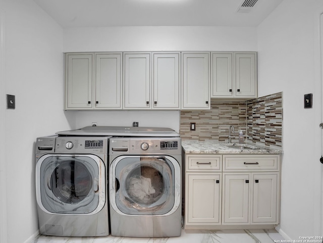 washroom with cabinets, independent washer and dryer, and sink