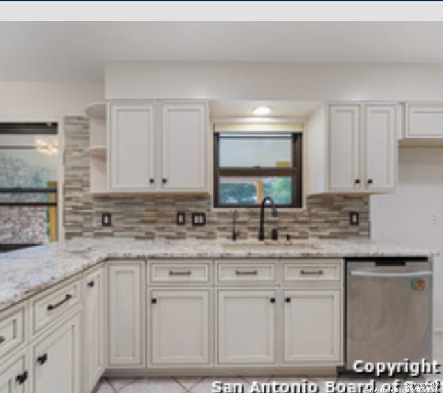 kitchen with white cabinets, sink, stainless steel dishwasher, decorative backsplash, and light stone countertops