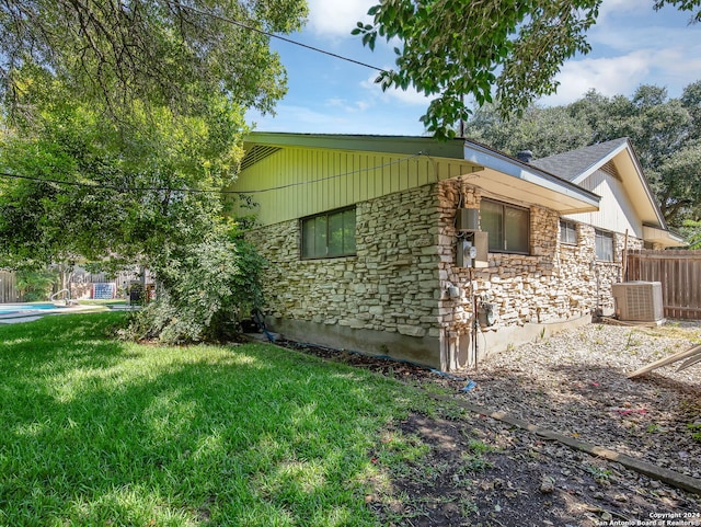 view of side of home featuring central AC unit and a yard