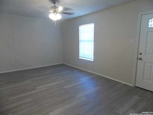 spare room featuring a textured ceiling, dark wood-type flooring, and ceiling fan