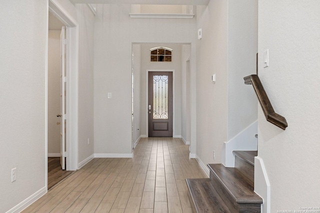 entryway with light wood-style floors, baseboards, and stairs