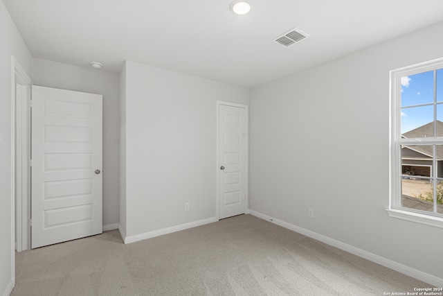 unfurnished bedroom with a closet, light carpet, and multiple windows