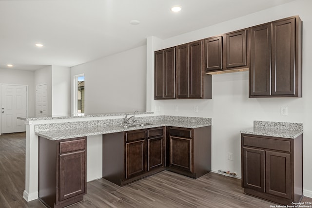 kitchen featuring hardwood / wood-style flooring, kitchen peninsula, sink, and dark brown cabinetry