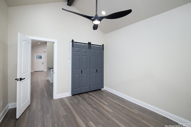 unfurnished bedroom with hardwood / wood-style floors, high vaulted ceiling, beam ceiling, ceiling fan, and a barn door