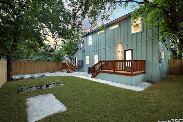 back house at dusk with a wooden deck and a yard