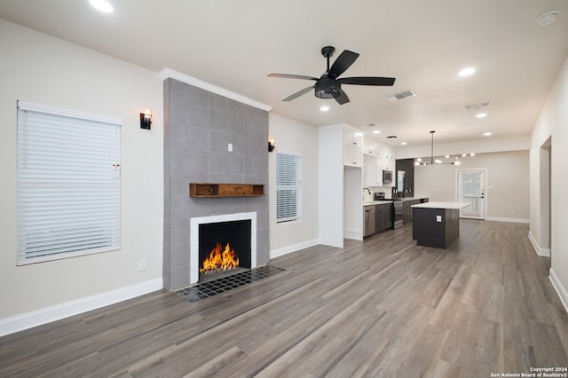 unfurnished living room featuring sink, a fireplace, hardwood / wood-style flooring, tile walls, and ceiling fan