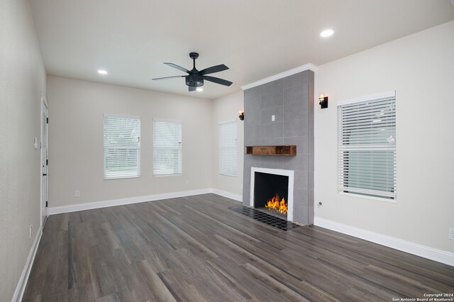 unfurnished living room with a fireplace, tile walls, ceiling fan, and dark hardwood / wood-style flooring