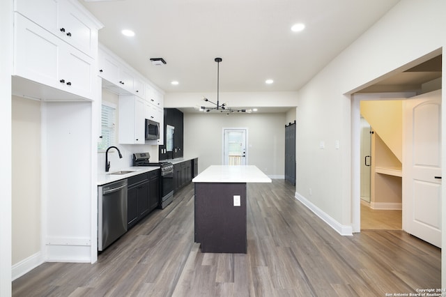 kitchen with appliances with stainless steel finishes, light hardwood / wood-style flooring, white cabinets, and a center island