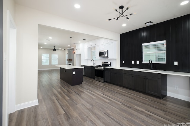 kitchen with a kitchen island, hardwood / wood-style floors, white cabinetry, appliances with stainless steel finishes, and sink