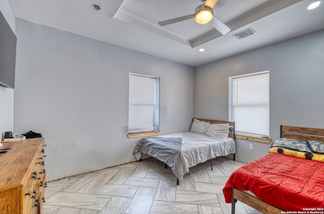 bedroom with ceiling fan and a tray ceiling