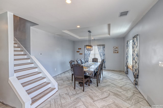 tiled dining space featuring a raised ceiling and a notable chandelier