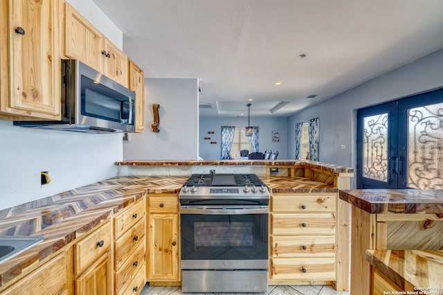 kitchen featuring kitchen peninsula, stainless steel appliances, and light brown cabinets