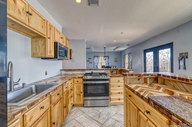 kitchen featuring light tile patterned flooring, sink, appliances with stainless steel finishes, light brown cabinets, and kitchen peninsula