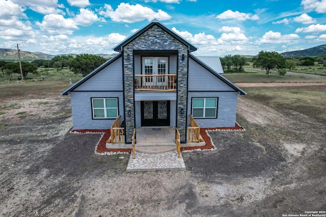 136 Cardinal Dr, Camp Wood, TX 78833 - view of front of house featuring a mountain view, a balcony, french doors, and stone siding