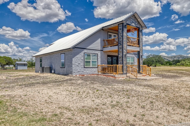 back of house featuring a balcony, central air condition unit, and a shed