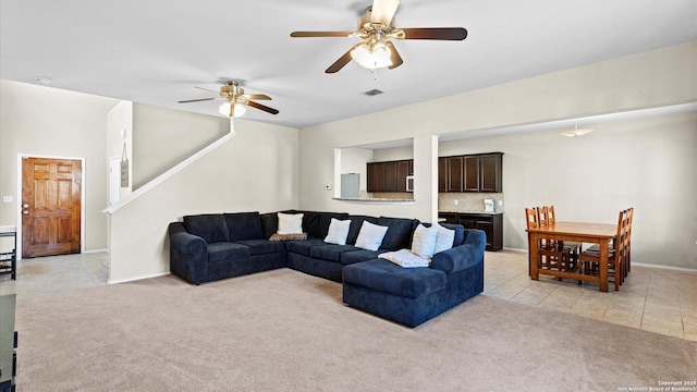 living area featuring light carpet, light tile patterned floors, ceiling fan, and visible vents