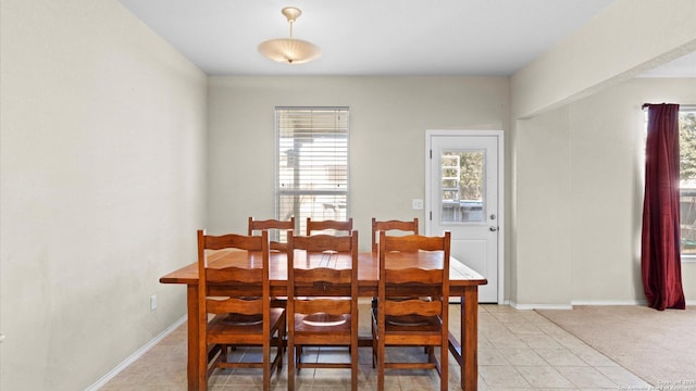 dining space with baseboards, light tile patterned floors, and light colored carpet