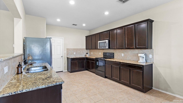 kitchen with dark brown cabinetry, tasteful backsplash, appliances with stainless steel finishes, light stone countertops, and a sink