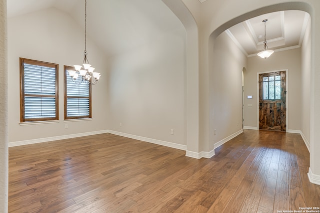 foyer featuring hardwood / wood-style floors, a raised ceiling, an inviting chandelier, and a high ceiling